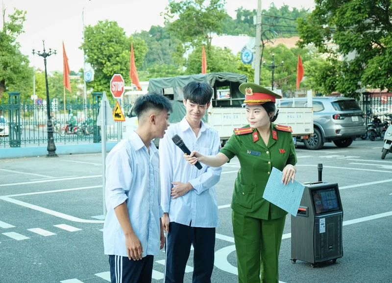 Nữ cán bộ công an cầm micro trao đổi trực tiếp với học sinh.