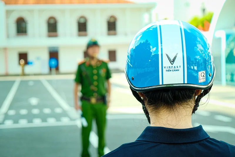 Cận cảnh mũ bảo hiểm màu xanh có chữ VinFast Tiến Cảnh trong khu vực hướng dẫn.