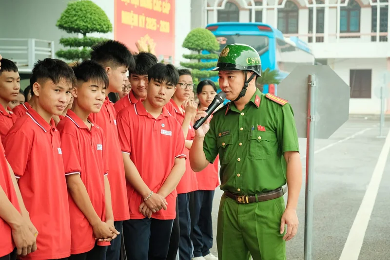 Cán bộ công an cầm micro trao đổi cùng nhóm người tham gia mặc áo đỏ.
